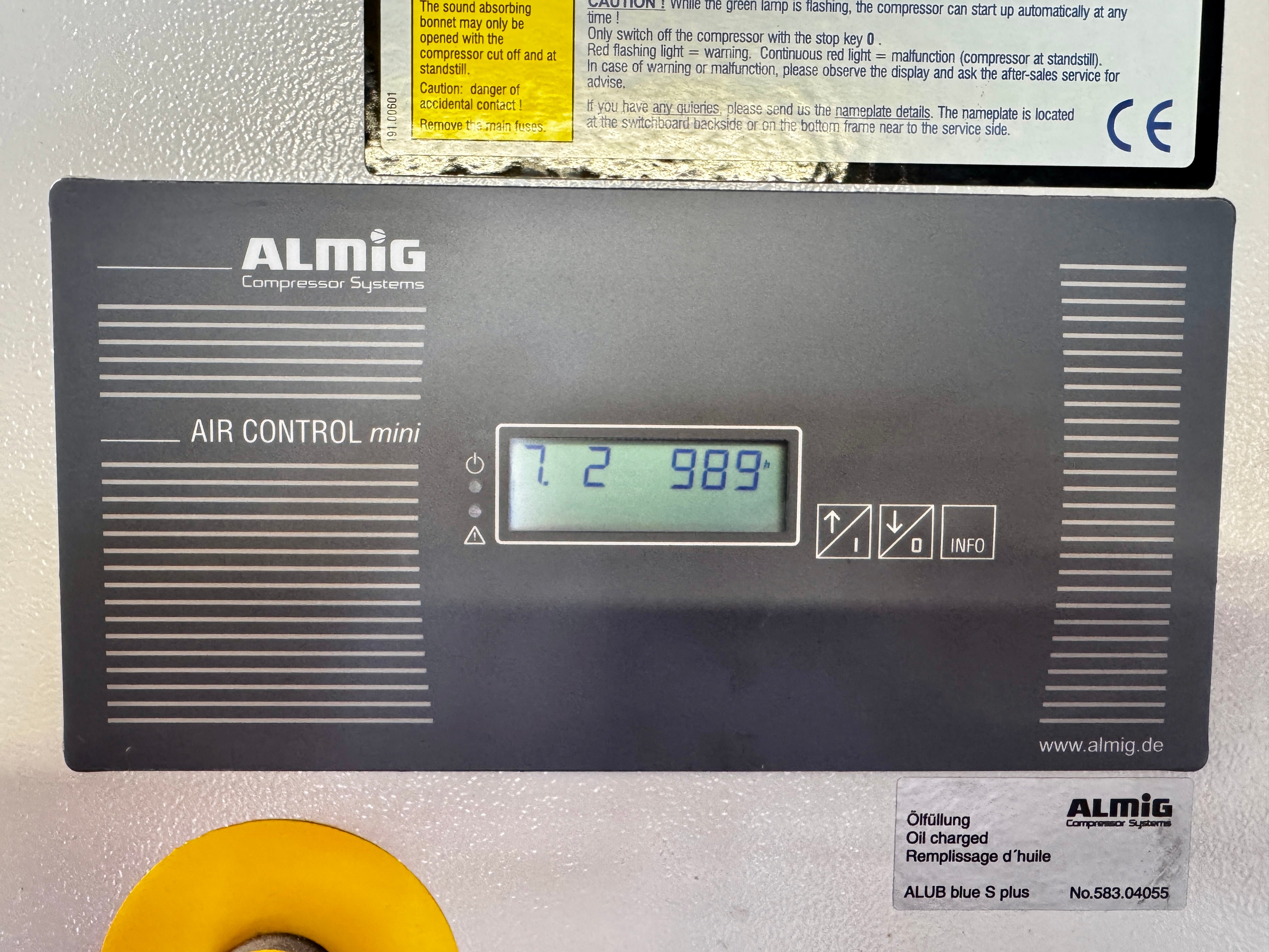 ALMig Air Control mini electronic pressure sensor for compressor oil level, showing a digital display on a dark gray panel mounted on a metallic surface.