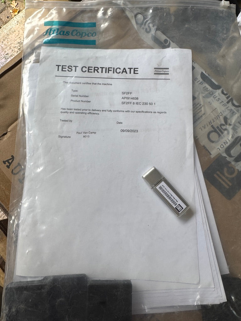 Test certificate and USB drive inside a clear plastic bag with Atlas Copco branding.