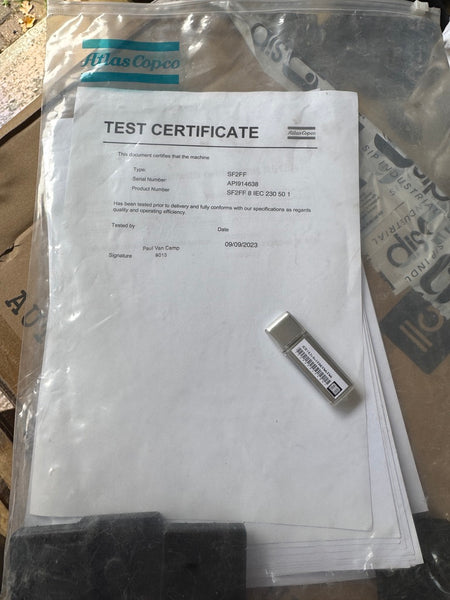 Test certificate and USB drive inside a clear plastic bag with Atlas Copco branding.