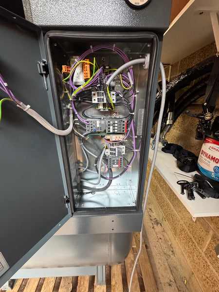 Open electronic cabinet with visible wiring and components on a wooden floor.