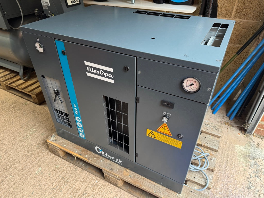 Atlas Copco air compressor on a wooden pallet with a concrete floor background