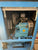 Close-up of a blue industrial machine cabinet showing internal components including a metal vented box, flexible hose, motor, and piping.