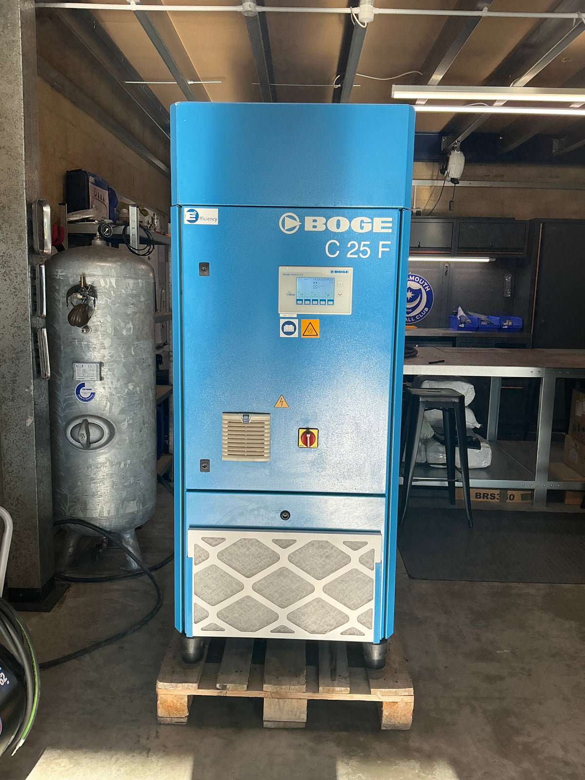 A blue BOGE C 25 F air compressor unit with an attached gray air tank, photographed in a workshop or industrial setting.