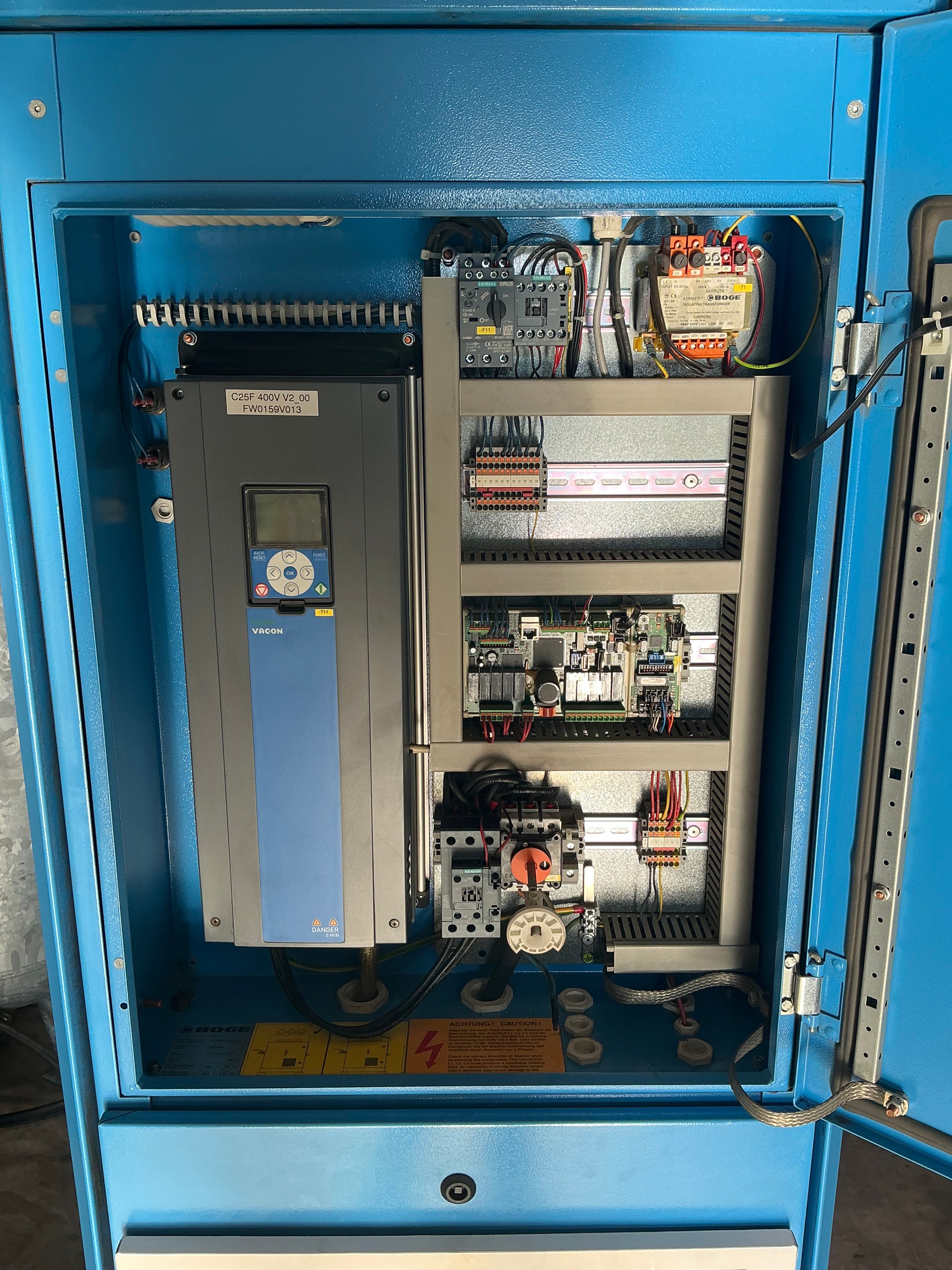 Open blue industrial electrical cabinet showing internal control panel components, wiring, and a gray drive unit.
