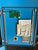 Open blue industrial control cabinet showing internal components including a green circuit board, beige metal housing, vent grille, and printed documentation on a blue panel.