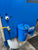 Blue machine with a cylindrical component labeled 'mif' on a concrete floor.