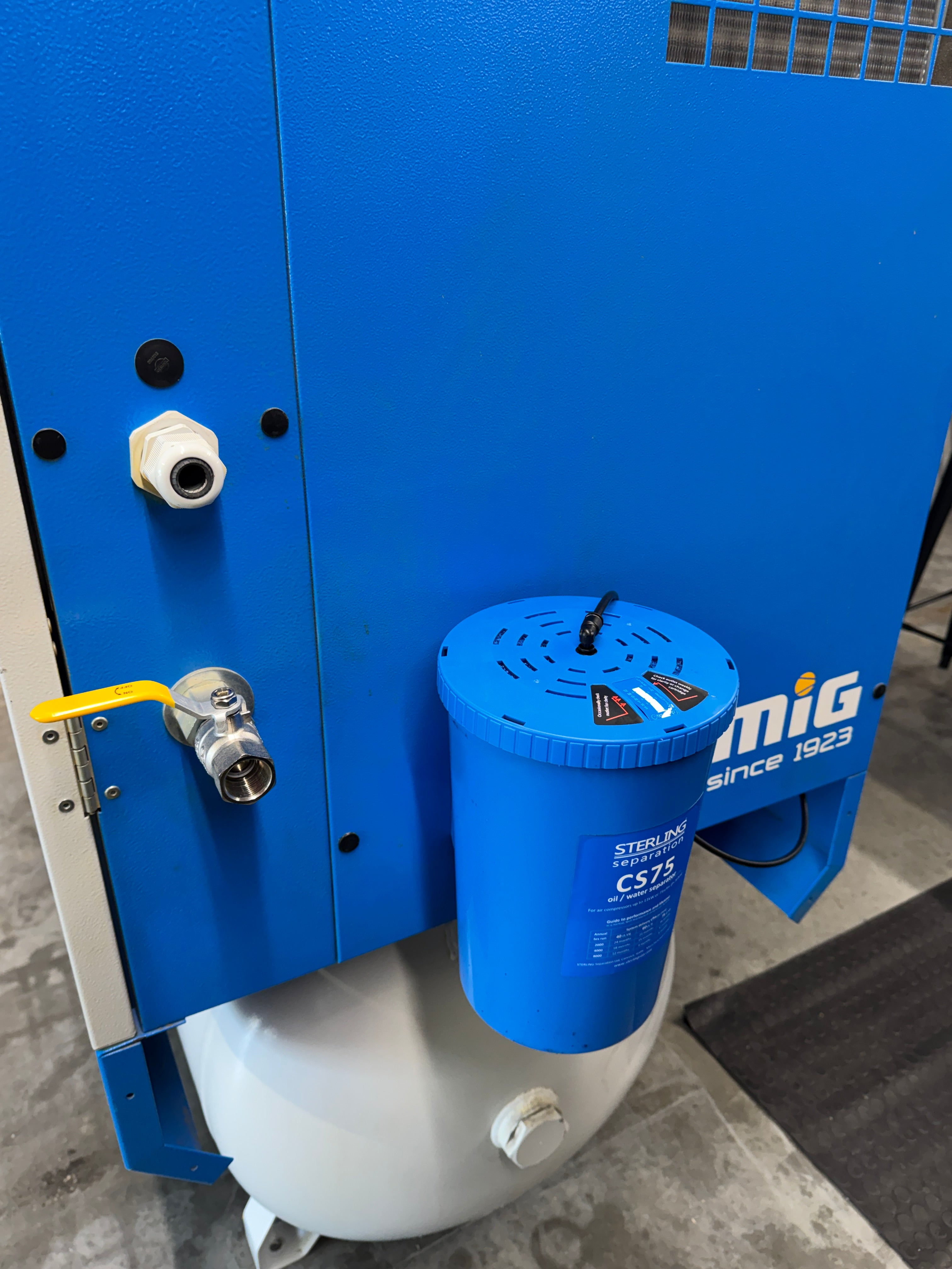 Blue machine with a cylindrical component labeled 'mif' on a concrete floor.