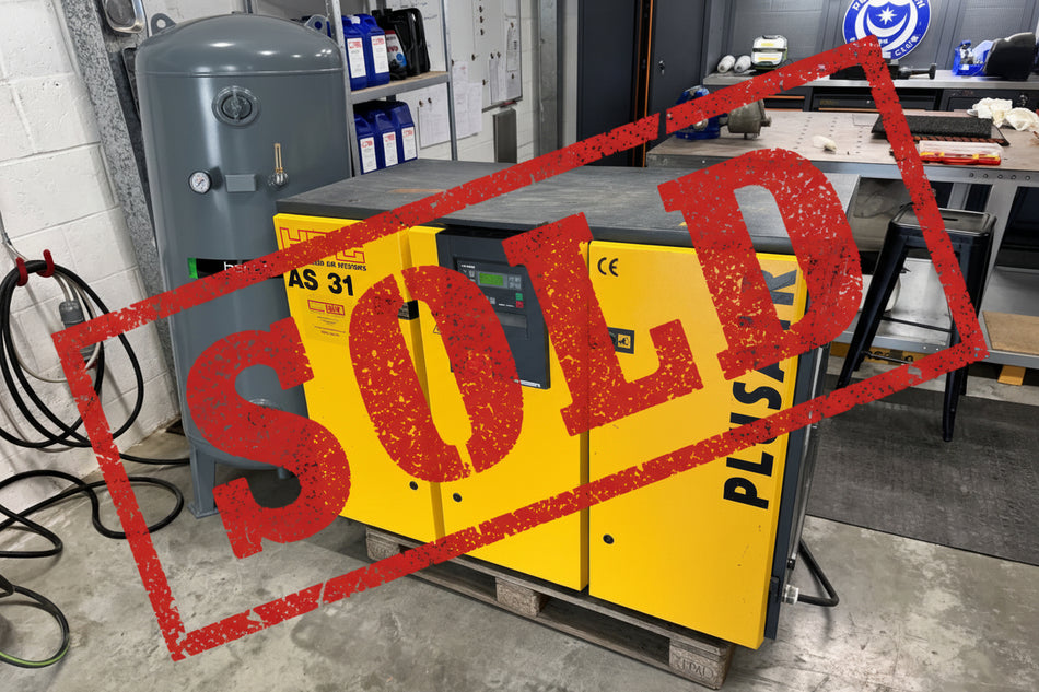 A yellow and gray Plusair air compressor with a digital control panel, sitting on a wooden pallet in a workshop next to a gray Hertz air tank.