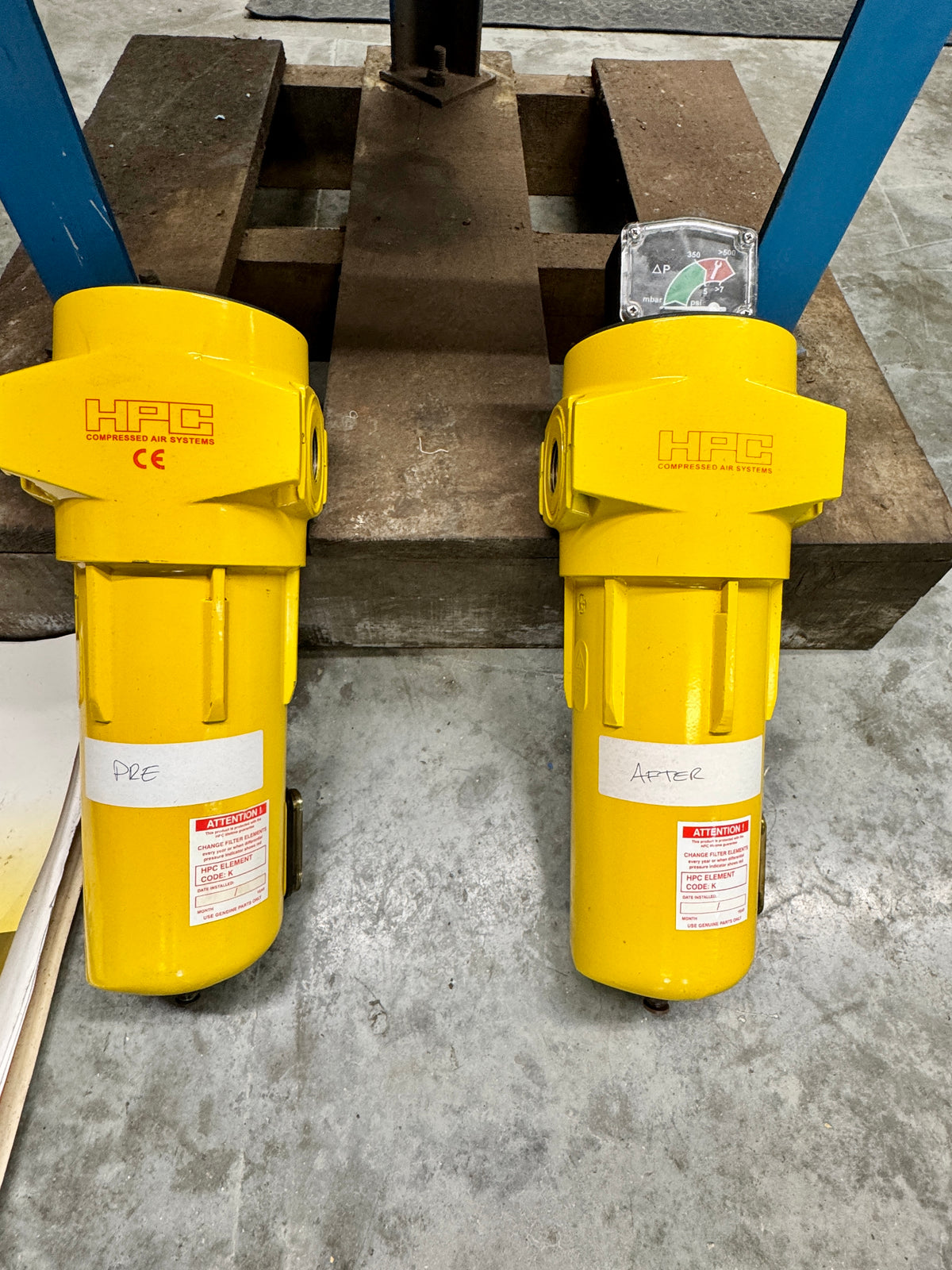 Two yellow HFC filters on a concrete floor with metal beams in the background.