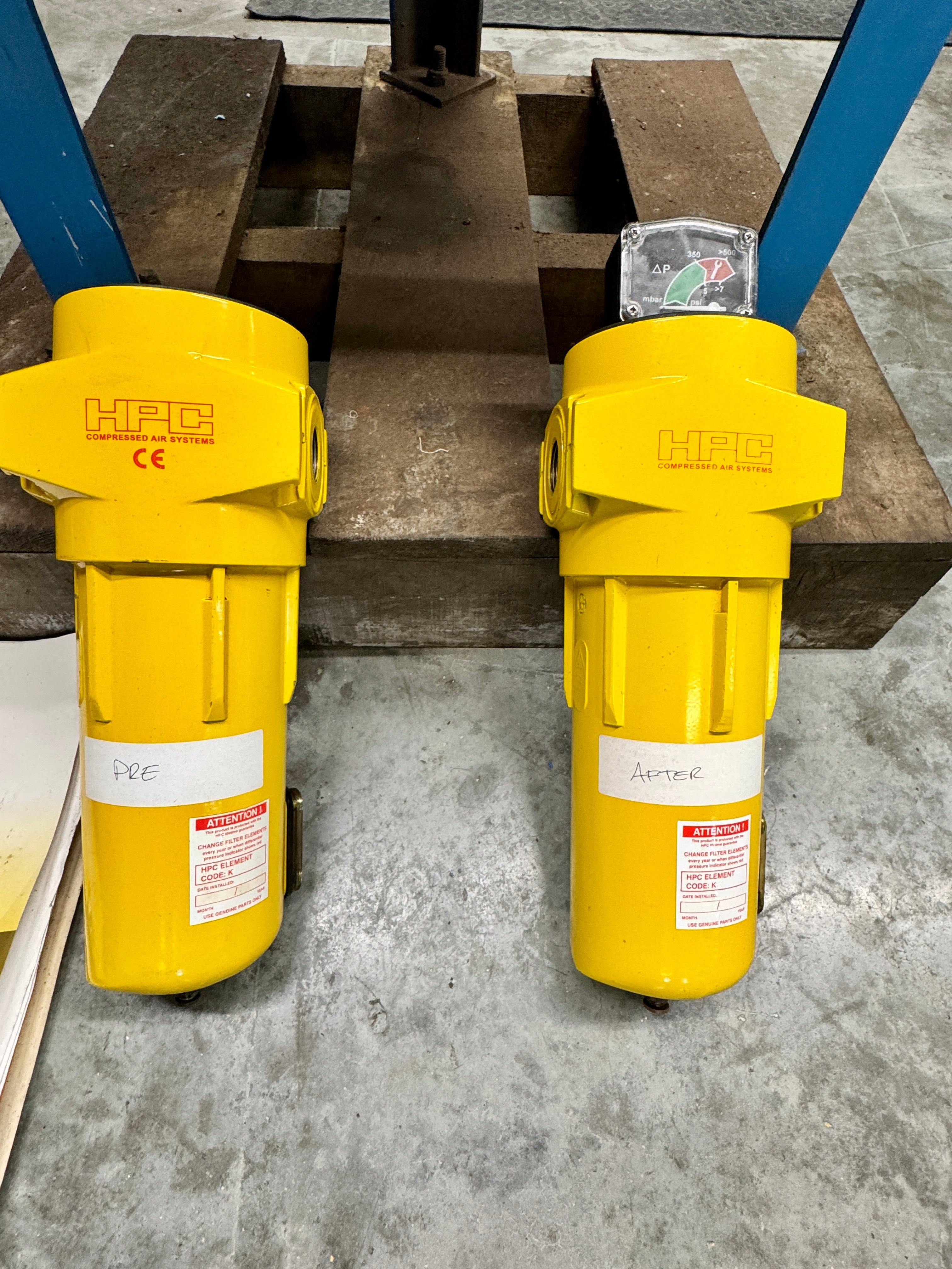 Two yellow HFC filters on a concrete floor with metal beams in the background.