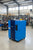 Blue CompAir compressor on a concrete surface with a building in the background