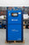Blue CompAir air compressor on a pallet outdoors with trees and a building in the background.