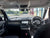The interior of a modern SUV or Land Rover vehicle, showing the dashboard, steering wheel, center console, and headliner, with a view of an outdoor parking lot through the windshield.