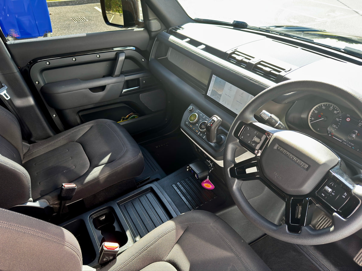 A clean, bright interior shot of a vehicle's cabin, showing the driver's side with a gray leatherette steering wheel, black seats, and a dark dashboard.