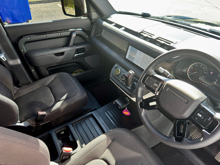 A clean, bright interior shot of a vehicle's cabin, showing the driver's side with a gray leatherette steering wheel, black seats, and a dark dashboard.
