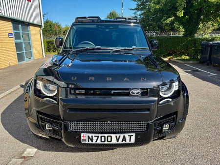A black urban SUV parked outdoors on a paved area, photographed from the front. The vehicle has a prominent front grille, LED headlights, and a license plate reading N700 VAT.