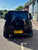 A black Land Rover Defender SUV photographed from the rear, parked on an outdoor paved area with a yellow UK license plate reading N700 VAT.