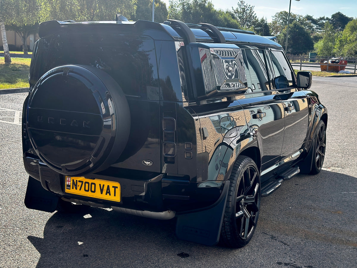 A glossy black custom Land Rover Defender SUV parked outdoors on a paved surface. The vehicle features a custom black hardtop roof, a black spare tire cover with 'FOCAR' lettering, a yellow license plate, and black aftermarket wheels.