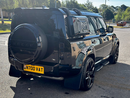 A glossy black custom Land Rover Defender SUV parked outdoors on a paved surface. The vehicle features a custom black hardtop roof, a black spare tire cover with 'FOCAR' lettering, a yellow license plate, and black aftermarket wheels.