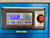 Close-up of a blue industrial machine control panel with a digital display, blue buttons, a gray faceplate, and a red emergency stop button labeled MC 41.