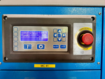 Close-up of a blue industrial machine control panel with a digital display, blue buttons, a gray faceplate, and a red emergency stop button labeled MC 41.