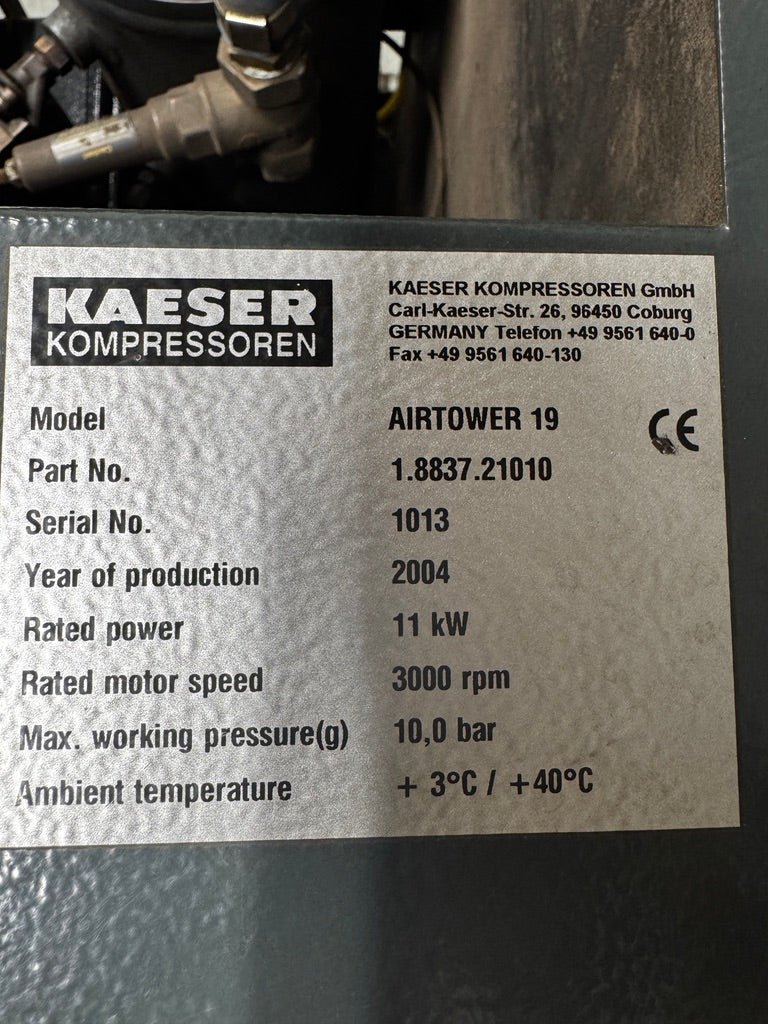 A close-up of a metal nameplate on industrial machinery showing the brand KAESER KOMPRESSOREN and model AIRTOWER 19 with technical specifications.