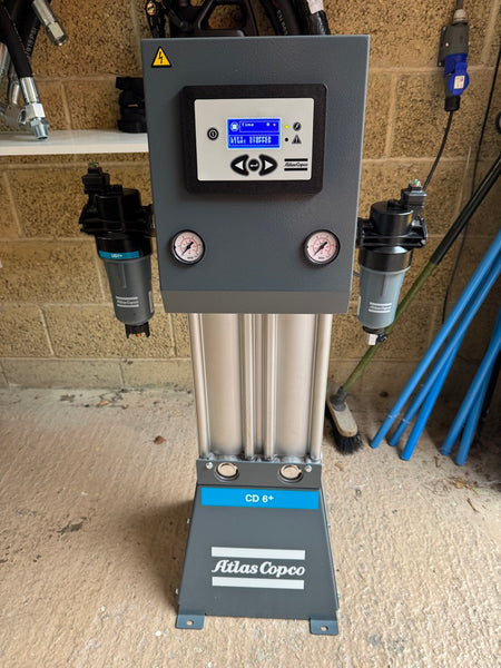 Atlas Copco air compressor with digital display and gauges on a concrete floor.