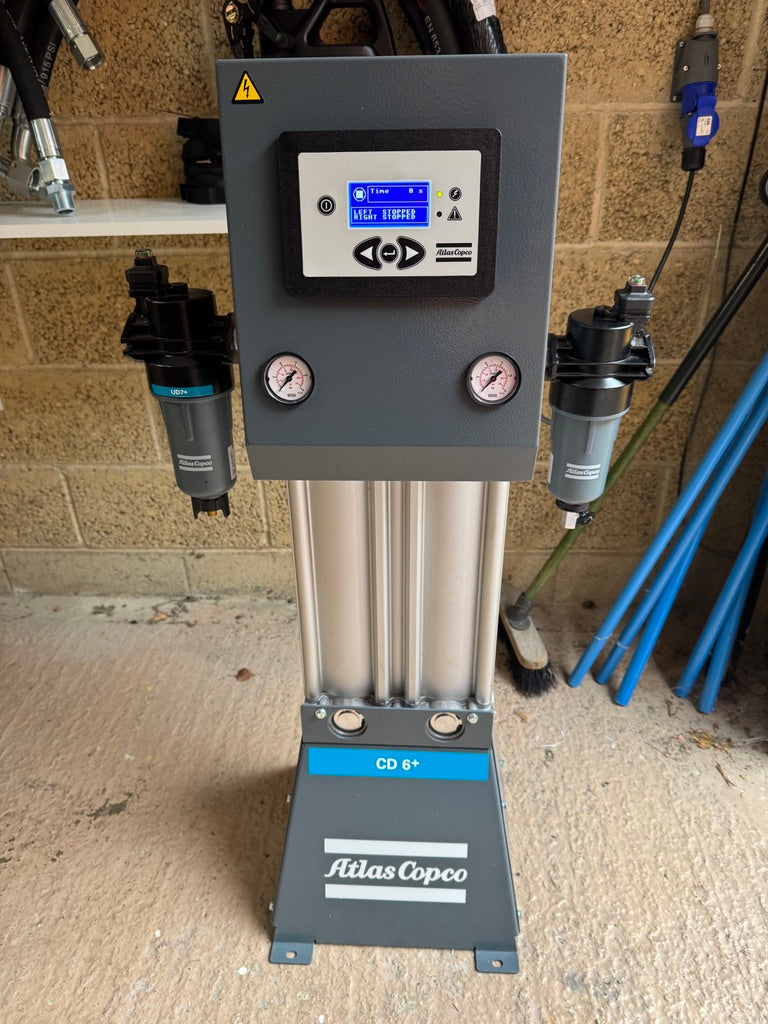 Atlas Copco air compressor with digital display and gauges on a concrete floor.