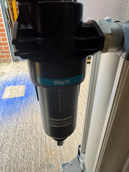 Atlas Copco air compressor filter with 'DDp7+' marking on a textured surface.