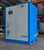 Blue air compressor with 'Almig' branding in a warehouse setting