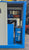 Blue industrial cabinet with various components inside, on a concrete floor.