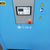 Blue industrial machine with control panel and warning symbols